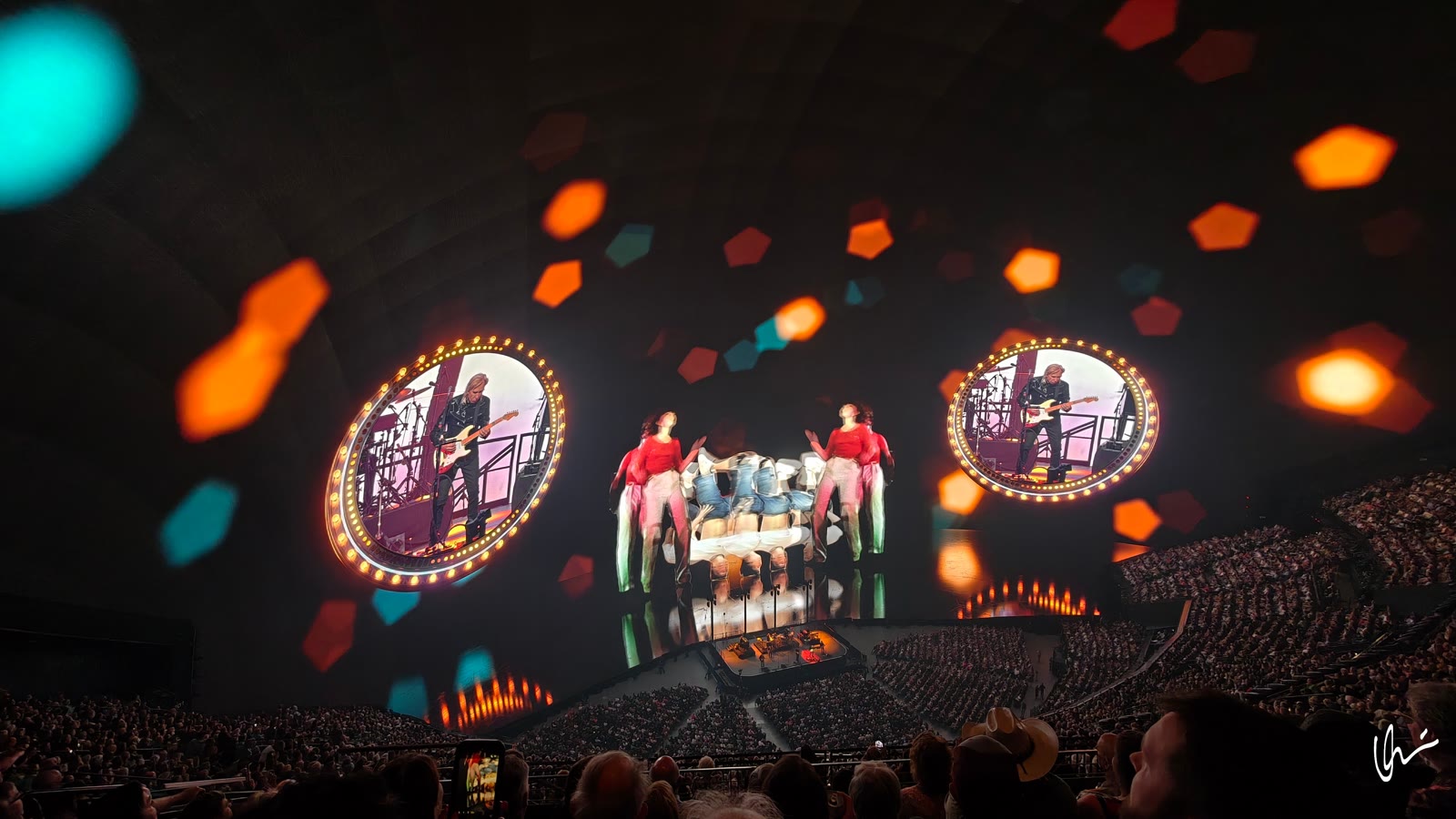 Guitarist in glowing circles and dancers on the Sphere dome, bokeh of lights over the full house