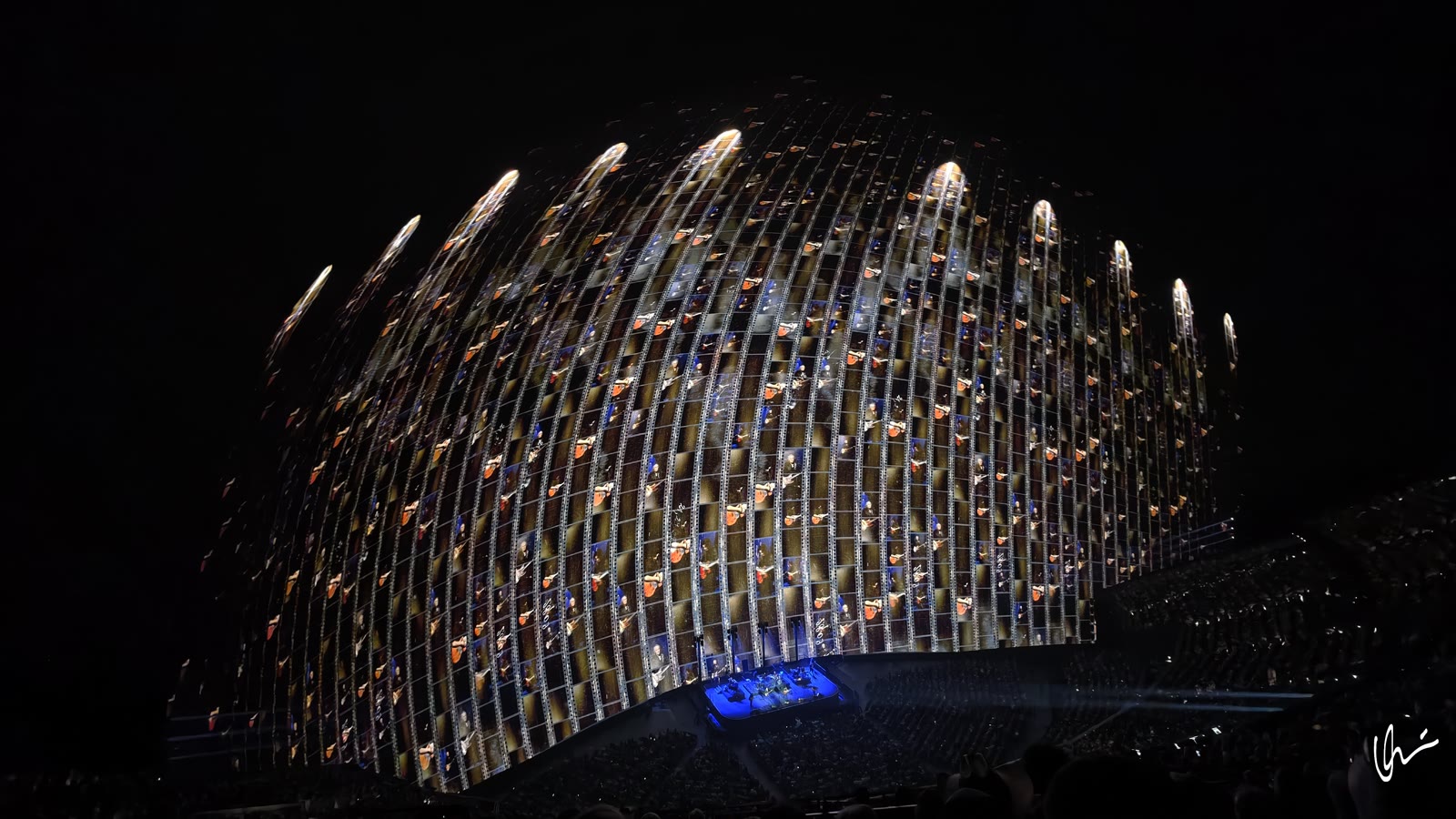 Sphere dome as a wall of filmstrips: frames from Eagles history, guitars and amplifiers, stage in blue light below